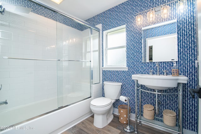 full bathroom featuring hardwood / wood-style floors, toilet, enclosed tub / shower combo, and sink