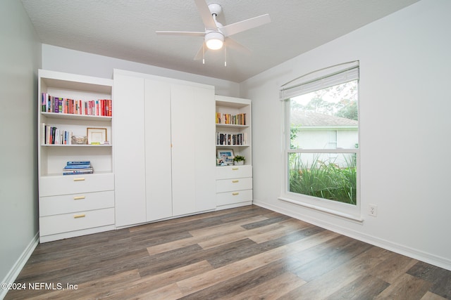 unfurnished bedroom with a textured ceiling, dark hardwood / wood-style flooring, and ceiling fan