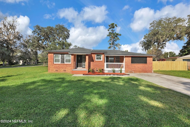 ranch-style home featuring covered porch and a front lawn