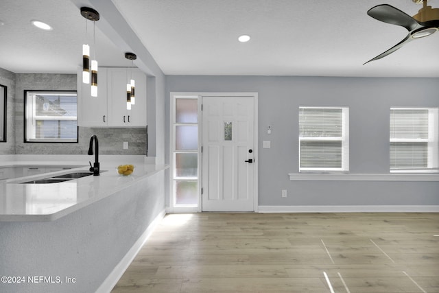 kitchen with white cabinets, decorative light fixtures, a healthy amount of sunlight, and light hardwood / wood-style flooring