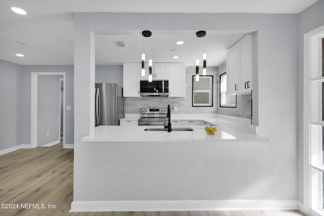 kitchen featuring sink, light hardwood / wood-style flooring, decorative light fixtures, white cabinetry, and stainless steel appliances