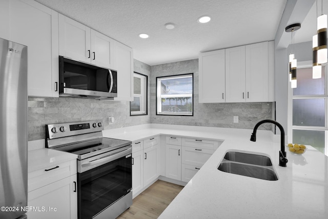 kitchen featuring sink, hanging light fixtures, a textured ceiling, white cabinets, and appliances with stainless steel finishes