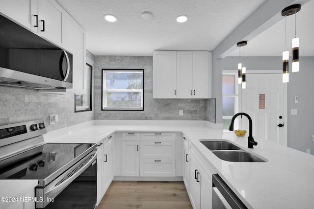 kitchen featuring white cabinets, sink, light wood-type flooring, appliances with stainless steel finishes, and decorative light fixtures