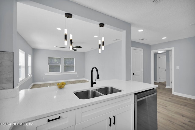 kitchen featuring stainless steel dishwasher, sink, decorative light fixtures, light hardwood / wood-style flooring, and white cabinetry