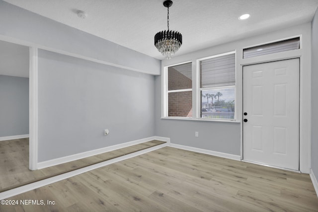 entrance foyer with a chandelier, a textured ceiling, and light wood-type flooring