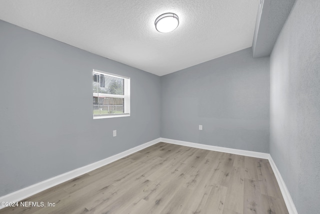 unfurnished room featuring a textured ceiling and light wood-type flooring