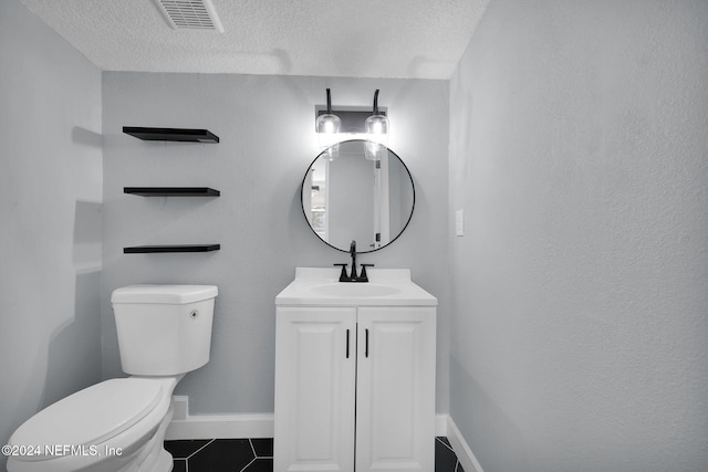 bathroom with tile patterned flooring, vanity, toilet, and a textured ceiling