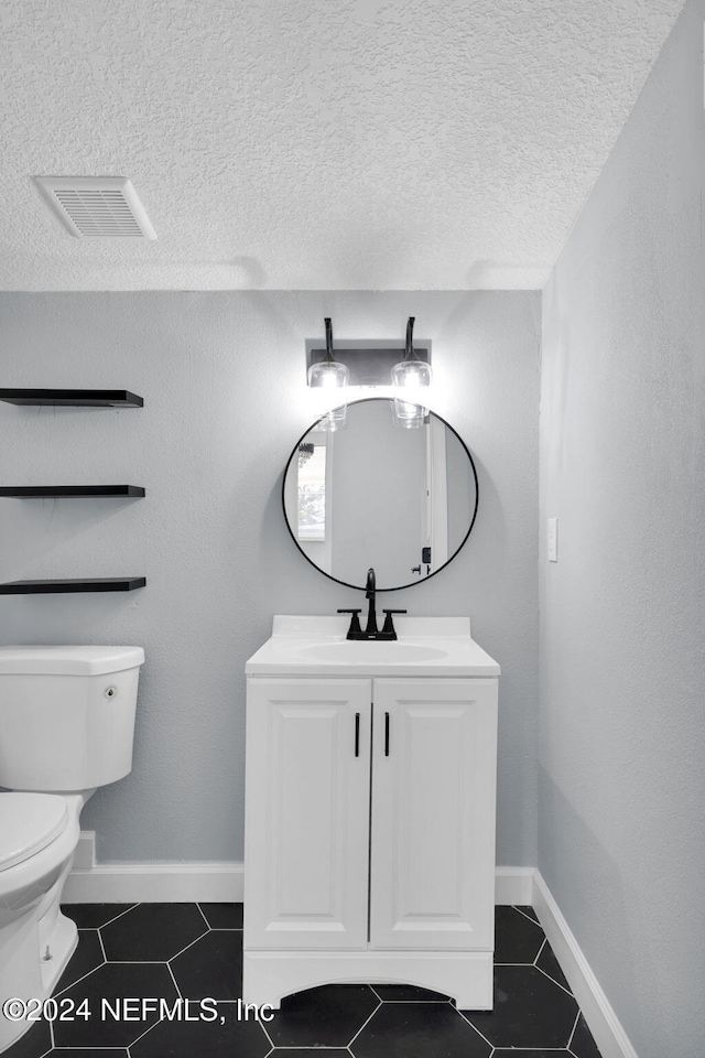 bathroom featuring tile patterned flooring, vanity, a textured ceiling, and toilet