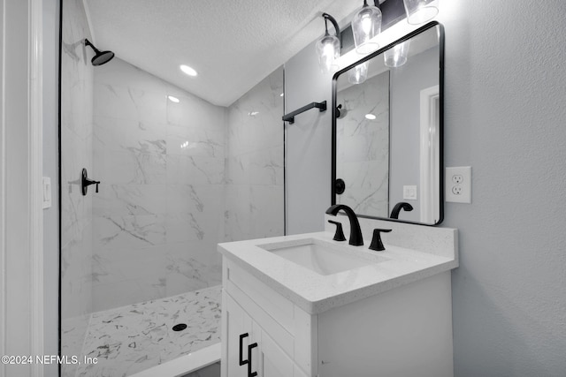 bathroom with a tile shower, vanity, and a textured ceiling