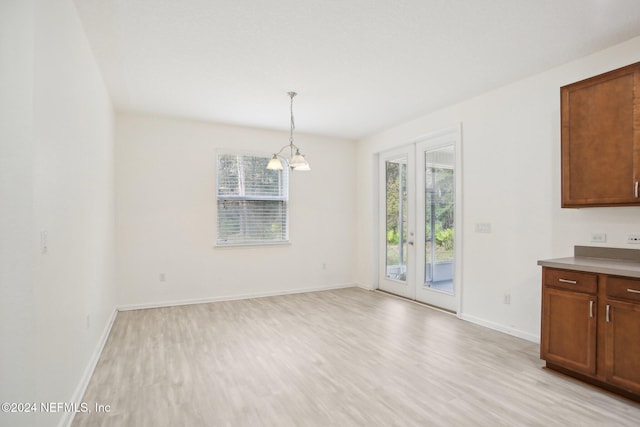 unfurnished dining area with light hardwood / wood-style floors and an inviting chandelier