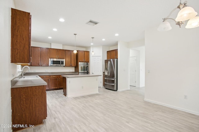 kitchen featuring a center island, hanging light fixtures, sink, appliances with stainless steel finishes, and light hardwood / wood-style floors