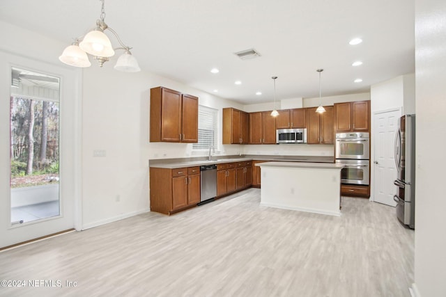 kitchen featuring a center island, stainless steel appliances, decorative light fixtures, and light hardwood / wood-style flooring