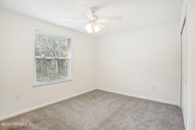 carpeted spare room featuring ceiling fan