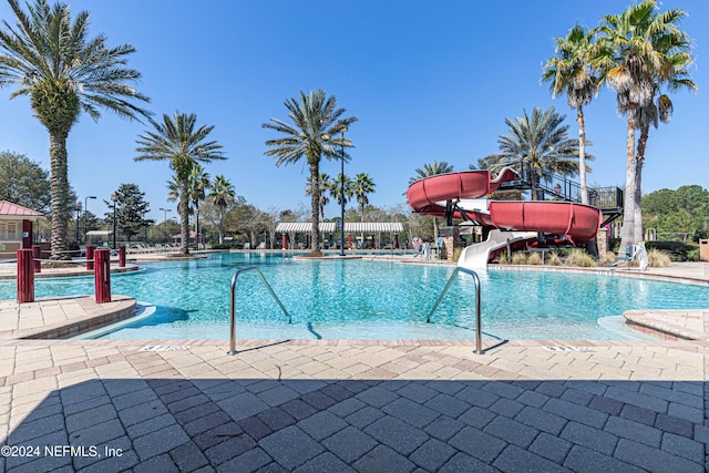 community pool with a patio area and a water slide