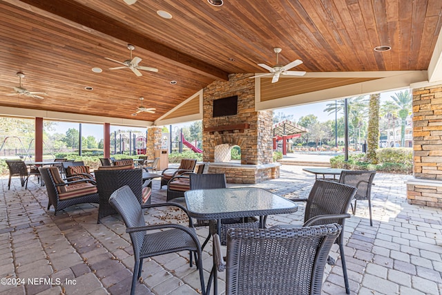 view of patio / terrace featuring outdoor dining area, an outdoor stone fireplace, and ceiling fan