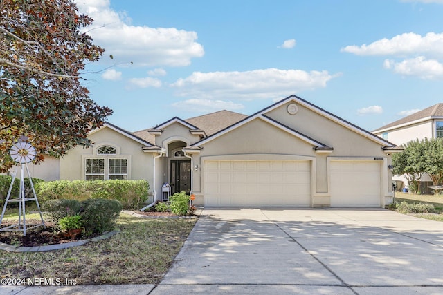 ranch-style home featuring a garage, driveway, and stucco siding