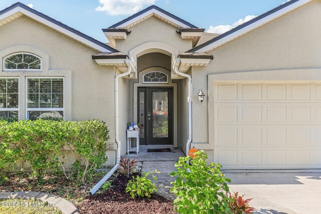 doorway to property with a garage and stucco siding