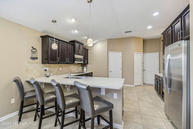 kitchen with kitchen peninsula, stainless steel appliances, sink, pendant lighting, and a breakfast bar area