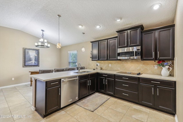 kitchen featuring lofted ceiling, sink, hanging light fixtures, kitchen peninsula, and stainless steel appliances