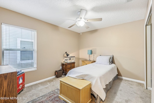 bedroom with a textured ceiling, ceiling fan, light carpet, and a closet