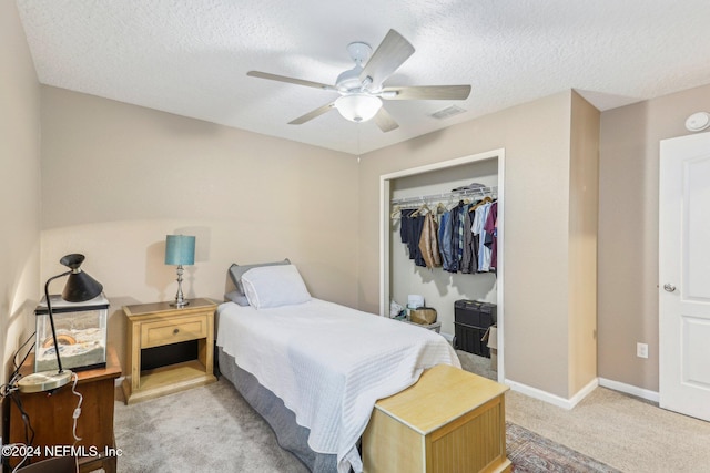 carpeted bedroom with a textured ceiling, a closet, and ceiling fan