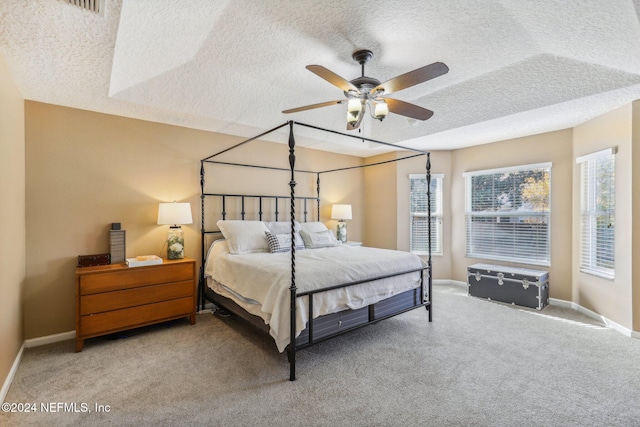 bedroom featuring ceiling fan, light carpet, and a textured ceiling