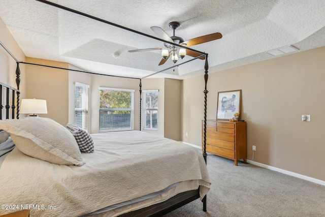 bedroom featuring a textured ceiling, light colored carpet, a raised ceiling, and ceiling fan