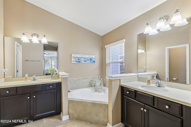 bathroom featuring vanity, vaulted ceiling, tile patterned flooring, a textured ceiling, and tiled bath