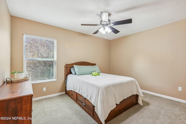 bedroom with a textured ceiling, light colored carpet, and ceiling fan