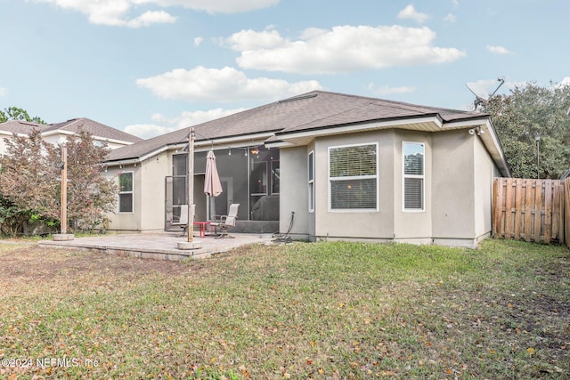 rear view of property with a patio, fence, a yard, roof with shingles, and a sunroom