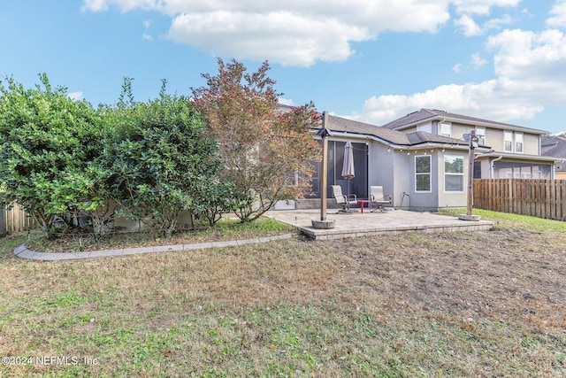 rear view of property with stucco siding, a patio area, a lawn, and fence private yard