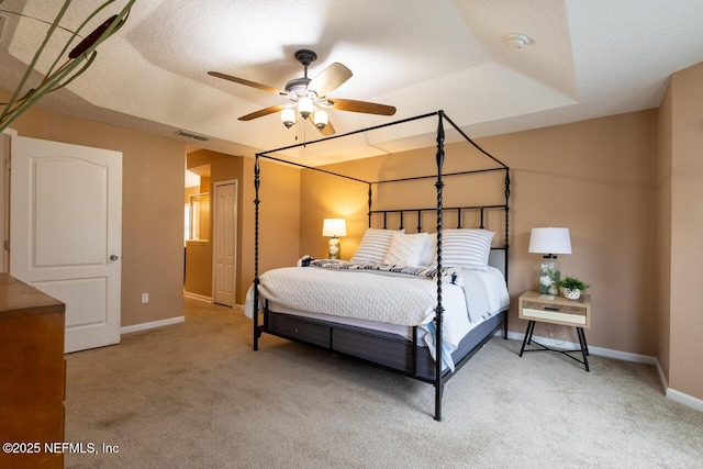 bedroom with a textured ceiling, light colored carpet, visible vents, and baseboards