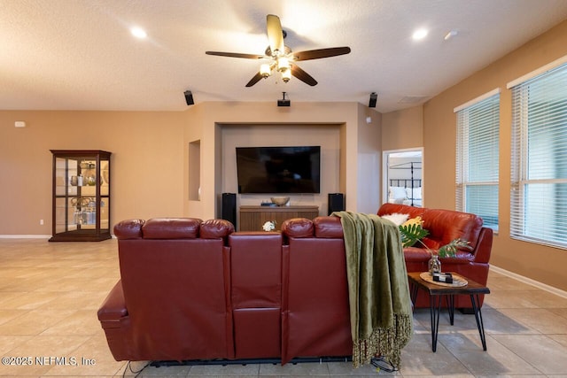 living area featuring baseboards, a textured ceiling, and ceiling fan