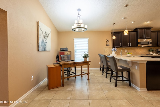 kitchen with stainless steel microwave, a kitchen breakfast bar, light countertops, light tile patterned floors, and decorative backsplash