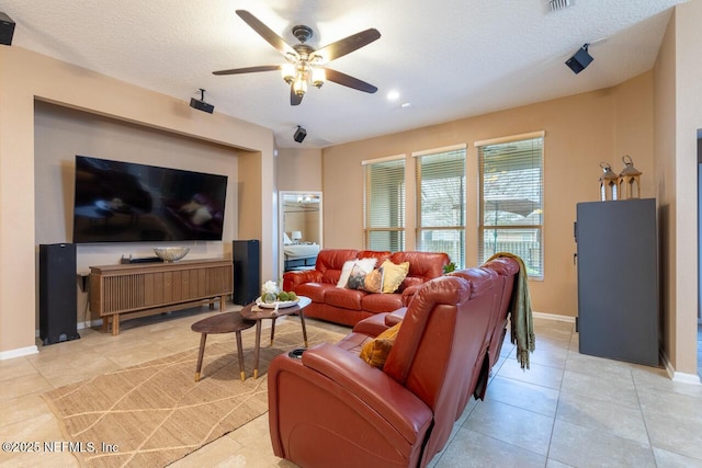 living room featuring ceiling fan, light tile patterned floors, baseboards, and a textured ceiling