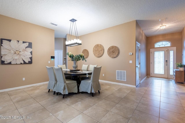 dining space featuring light tile patterned floors, visible vents, a textured ceiling, and a chandelier