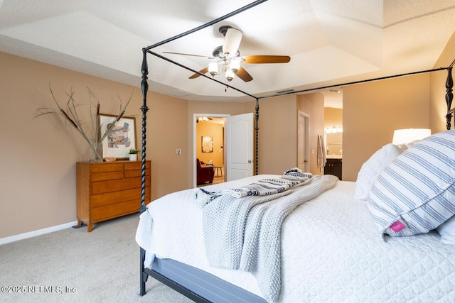 bedroom featuring light carpet, a ceiling fan, ensuite bathroom, and baseboards