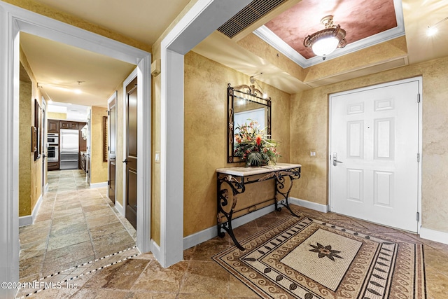 entryway with a raised ceiling and crown molding