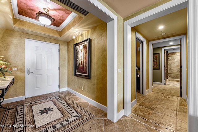 entrance foyer with a raised ceiling and crown molding