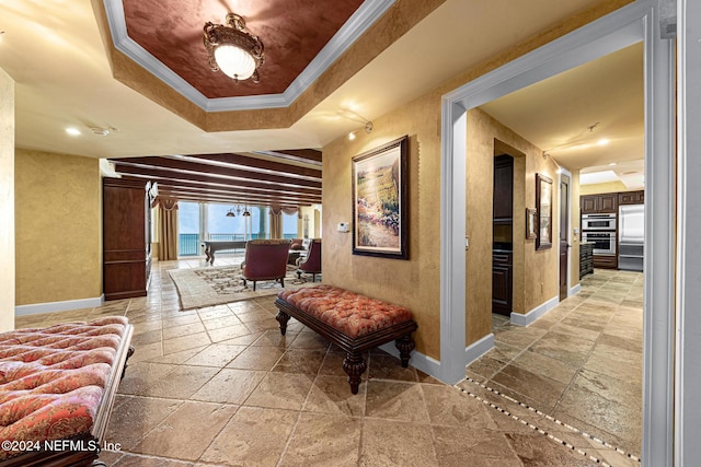 hallway with a tray ceiling, crown molding, and a water view