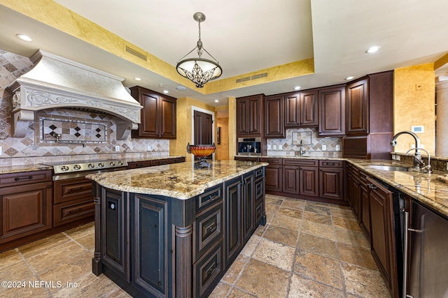 kitchen featuring premium range hood, pendant lighting, stainless steel gas stovetop, dark brown cabinets, and a kitchen island