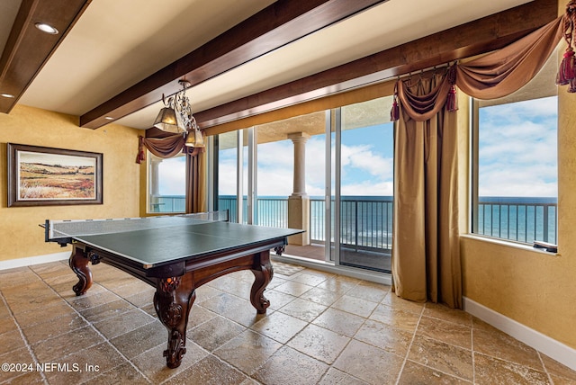 game room with beam ceiling and a water view