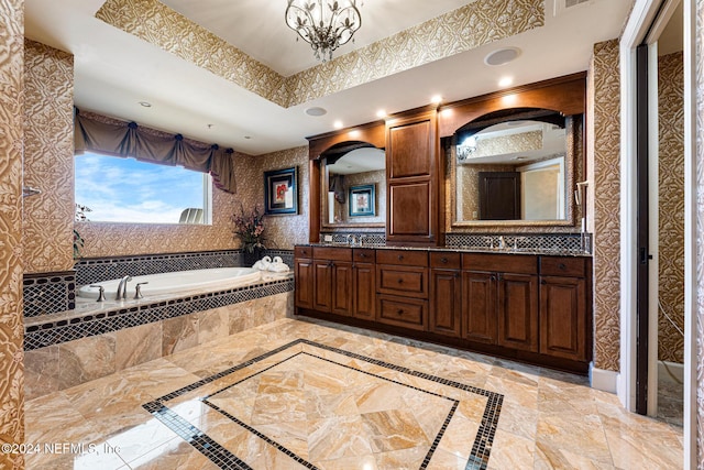 bathroom featuring vanity, a relaxing tiled tub, a tray ceiling, and a notable chandelier