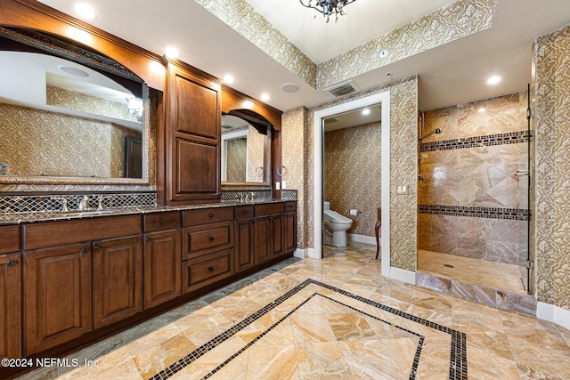 bathroom with tiled shower, vanity, toilet, and a bidet