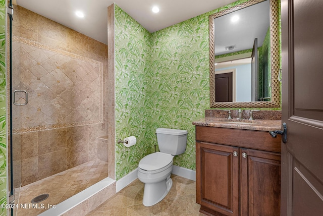 bathroom with tile patterned flooring, vanity, toilet, and tiled shower