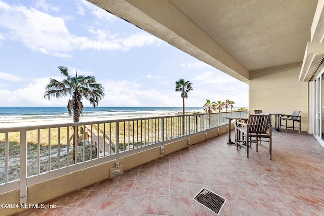 view of patio / terrace featuring a beach view, a water view, and a balcony