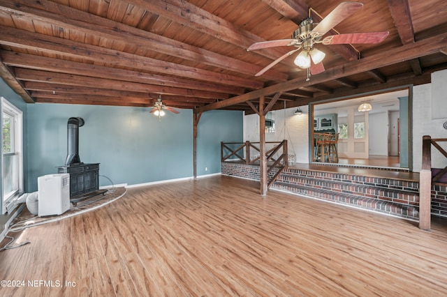 unfurnished living room with beam ceiling, wood-type flooring, a wood stove, and wood ceiling