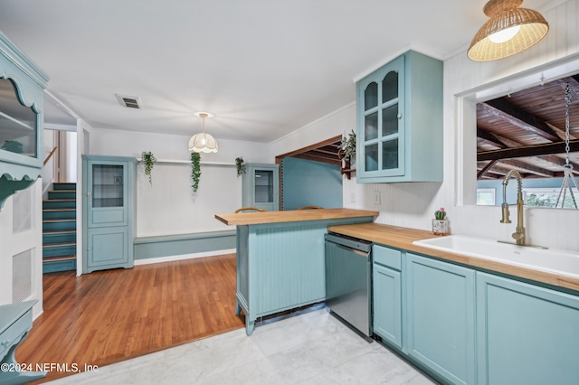 kitchen with pendant lighting, dishwasher, blue cabinets, sink, and light hardwood / wood-style flooring