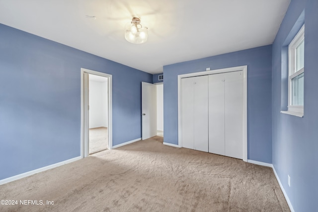 unfurnished bedroom featuring light carpet and a closet