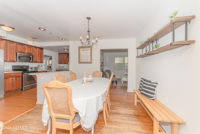 dining space featuring light wood-type flooring and a chandelier